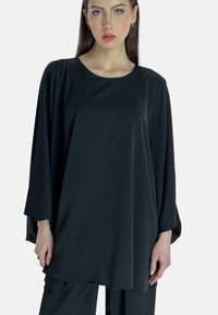 Top negro de corte holgado con escote redondo y mangas murciélago. Tejido liso con caída fluida, que ofrece una silueta relajada.