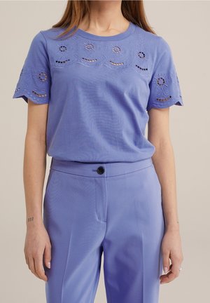 Haut violet clair à manches courtes avec un motif floral brodé et des découpes aux manches, accompagné d'un pantalon violet assorti.