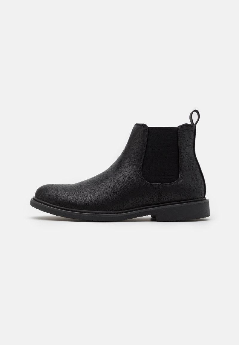 Bottine Chelsea en cuir noir avec panneau latéral élastique et languette de tirage sur fond blanc, montrée en profil droit.