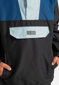 Czarna kurtka z niebieskim i jasnoniebieskim kolorowym wzorem. Posiada przednią kieszeń oraz naszywkę z logo. Wykonana z gładkiego, lekkiego materiału.