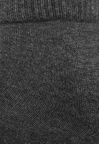 Dark gray knitted sock with a ribbed cuff, featuring a smooth texture and a consistent pattern. The design emphasizes elasticity and comfort.