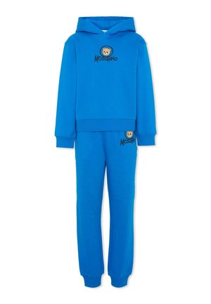 Niebieski komplet bluzy z kapturem i spodni dresowych z misiem i logo "Moschino" na klatce piersiowej i udzie, ściągacze w rękawach i pasie, model nakładany.