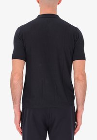 Polo nero con maniche corte, tessuto strutturato, colletto e polsini a coste e orlo dritto. Design semplice senza loghi visibili.