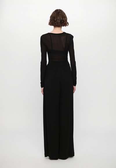 Black, long-sleeve top with sheer fabric and layered design, paired with wide-leg black trousers. Smooth texture and minimalist style.