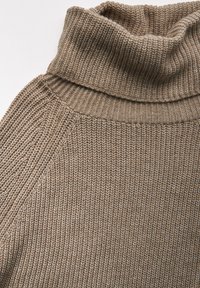 Brun stickad turtleneck-tröja med ribbad textur, med hög krage och raglanärmar för en avslappnad passform.