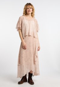 Abito midi rosa chiaro con un pattern paisley testurizzato, maniche a volantino corte e orlo asimmetrico. Abbinato a stivali marroni con lacci.