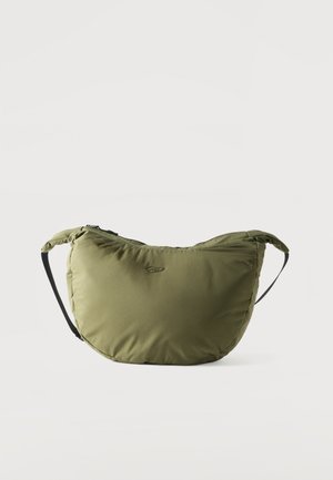 Oliwkowa zielona pikowana torba na ramię z czarnym regulowanym paskiem i małym logo z przodu, przedstawiona na białym tle.