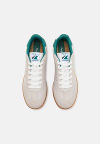 Zapatillas blancas y grises con toques en teal, materiales de ante y cuero, punta redonda, cordones blancos y suela de goma texturizada.