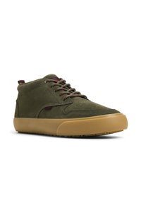Zapatillas altas de ante verde oliva con suela de goma marrón, cordones acentuados en rojo y verde, y detalle perforado en la puntera.