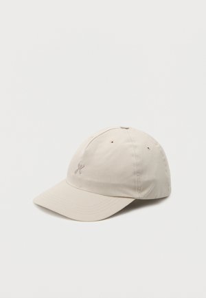 Casquette de baseball beige à visière courbée avec petit logo brodé sur l'avant, présentée sur un fond clair uni.