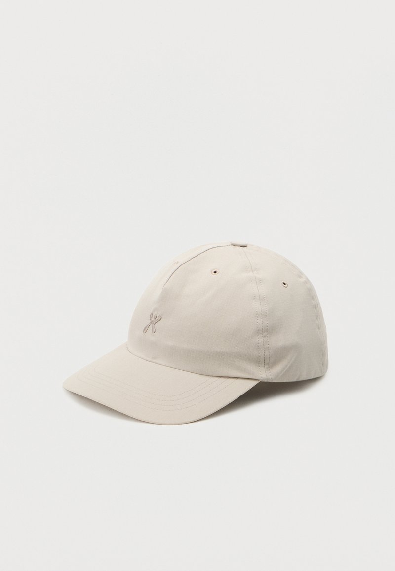 Beige Baseballkappe mit gebogenem Schirm und kleinem, besticktem Logo auf der Vorderseite, dargestellt vor hellem, schlichter Hintergrund.