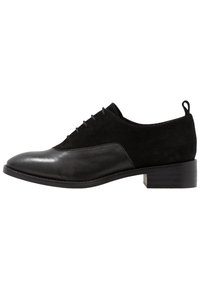 Chaussure habillée noire en cuir lisse et en daim. Bout rond, petit talon bloc et fermeture à lacets.