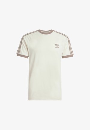 Kreem värvi lühikeste varrukatega t-särk raglan disainiga, pruunid detailid krael ja varrukatel, kolmerealine pruun triip ning brodieritud logo.