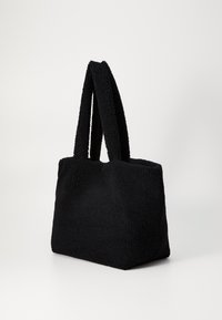 Μαύρη τσάντα tote κατασκευασμένη από υφασμάτινο υλικό με υφή, διαθέτοντας δύο κοντές, παχιές λαβές και απλή ορθογώνια μορφή. Χωρίς ορατό υλικό ή διακοσμητικά στοιχεία.