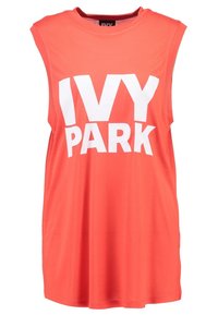 Koralfarvet ærmeløs tunika med rund hals, prydet med iøjnefaldende hvid "IVY PARK"-bogstaver på forsiden, lavet af blødt, åndbart stof.