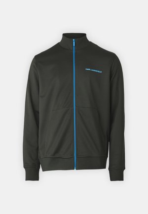 Giacca zip-up verde scuro con colletto alto, cerniera blù e logo discreto. Presenta tasche laterali e polsini a costine per un look aderente.