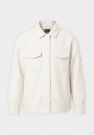 Valkoinen teksturoidusta kankaasta valmistettu takki, jossa on kaulus, pitkät hihat, painonapillinen suljenta ja kaksi etutaskua läpällä.