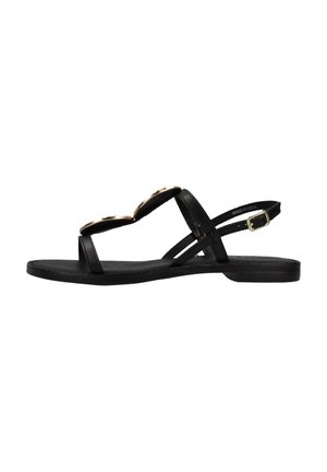 Sandal negra con dos acentos circulares dorados, suela plana y múltiples correas que cruzan el pie. Incluye una correa ajustable para el tobillo.