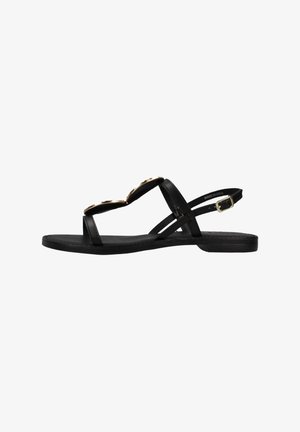 Sandal nero con due accenti circolari dorati, suola piatta e multiple cinghie che si incrociano sopra il piede. Include una cinghia regolabile alla caviglia.