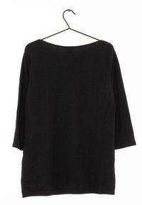 Musta, pitkähihainen paita, jossa on leveä pääntie, valmistettu pehmeästä kankaasta. Ripustettuna mustalle koukulle, esittää yksinkertaista, koristamatonta muotoilua.