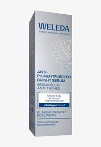 Opakowanie serum Weleda przeciw przebarwieniom, prostokątne pudełko; srebrne tło, niebieski tekst, biała ilustracja kwiatowa, czytelne informacje o składnikach.