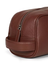 Braune Leder-Waschzeugtasche mit Reißverschluss, runder Form und einem seitlichen Griff für einfachen Transport. Strukturiert Oberfläche mit sichtbaren Nähten.