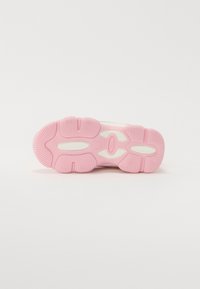 Fehér sneaker rózsaszín gumitalppal, texturált mintázattal, középen a FILA logóval. A dizájn sportos és modern.