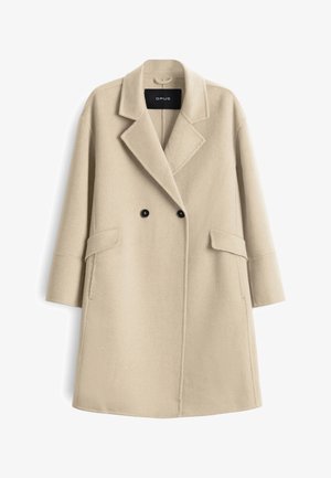 Cappotto in misto lana beige con design doppiopetto, rever a punta, due tasche laterali e bottoni neri a contrasto. Texture liscia.