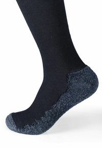 Calzino nero con una spessa copertura grigia testurizzata sulla heel, sulla suola e sulle punte, mostrato su un piede sollevato su uno sfondo bianco.