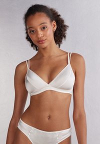 Bralette en satin blanc avec des bretelles fines et ajustables, décolleté en V, texture douce et culotte taille haute assortie.