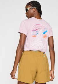 Ροζ ανοιχτό μπλουζάκι με γραφικό όρους και πολύχρωμους ουρανούς στην πλάτη. Συνδυασμένο με μπεζ σορτς που έχουν πίσω τσέπη και ελαστική μέση.