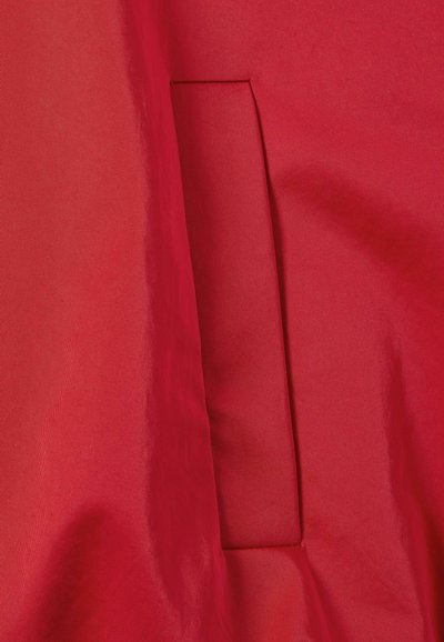 Tessuto rosso con una texture liscia e una tasca nascosta integrata nel design, caratterizzato da una forma pulita e semplice.