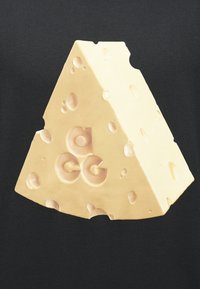 Τρίγωνο τυριού σε ελβετικό στιλ με τρύπες σε μαύρο φόντο, με ανάγλυφα μικρά γράμματα "a", "c" και "g".