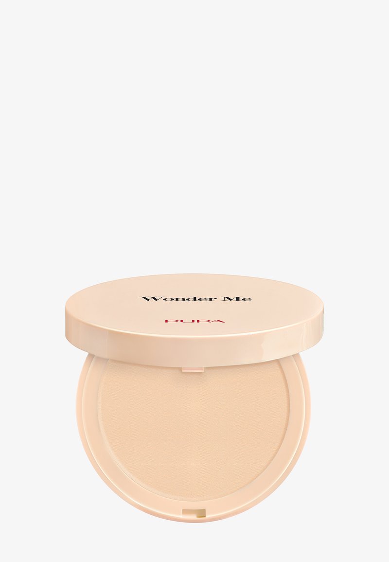 Poudre compacte dans un étui élégant beige clair. Le couvercle porte l'inscription « Wonder Me » en texte noir et « PUPA » en rouge. La surface intérieure montre une texture de poudre fine.