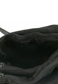 Interior de bolso de tela negra con un bolsillo con cremallera y textura suave. Presenta un contorno suave, diseño minimalista y sin patrones visibles.