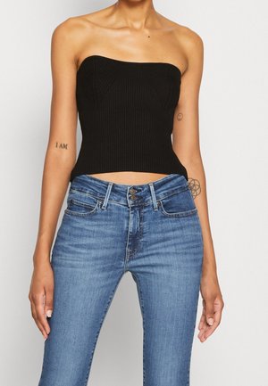 Zwarte geribbelde strapless top gecombineerd met blauwe denim jeans met een knoopsluiting, klassieke vijfzakkenontwerp en een licht vervaagde kleur.