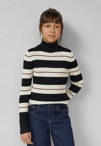 Geribde coltrui in zwart, crème en bordeaux gestreept. Slim fit met lange mouwen. Gecombineerd met blauwe denim jeans.