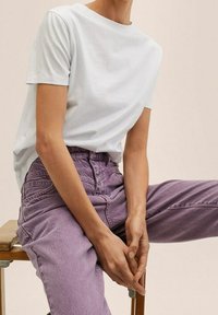 Camiseta de algodón azul claro de manga corta, combinada con unos vaqueros lavanda desgastados de cintura alta. Ambas prendas tienen un corte casual.