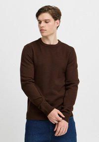 Brauner Strickpullover mit Rundhalsausschnitt, Rippbündchen und Saum. Verfügt über eine enganliegende Passform, ideal zum Layering.
