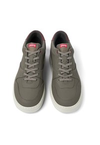 Grå lädersneakers med en slät textur, med en vit gummisula, grå snören och en liten röd CAMPER-logga på tungan.