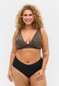 Lauva raksta bikini augšdaļa ar dziļu izgriezumu un bieziem siksniņām, savienota ar augstas jostas melnu apakšdaļu ar mežģīņu akcentiem.