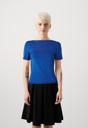 Top azul de manga corta con escote barco, combinado con una falda negra plisada. El top tiene una textura suave y un diseño ajustado.