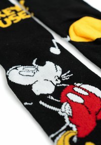 Calzini neri con un design di Topolino bianco, dettagli rossi, note musicali e dettagli gialli. Realizzati in materiale morbido e elasticizzato.