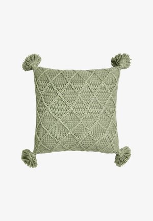 Grünes gestricktes quadratisches Kissen mit Diamantmuster und Quasten an jeder Ecke auf weißem Hintergrund.