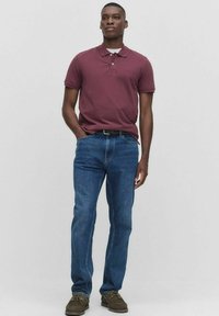 Mörkröd polo skjorta med krage, kombinerad med blå denimjeans och bruna skor. Outfiten har en klassisk passform och en enkel design.