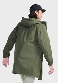 Veste olive verte résistante à l'eau avec capuche, poignets élastiques et évents zippés ; présente une coupe droite et un branding minimaliste sur la manche.