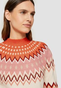 Strickpullover mit hohem, rundem Halsausschnitt und einem Zickzackmuster in Orange-, Rosa- und Cremetönen. Strukturierter, warmer Stoff.