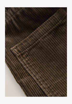 Barna kordbársony anyag függőleges csíkozással, varrással és zsebfelszereléssel, kiemelve a puha textúrát és gazdag színt.