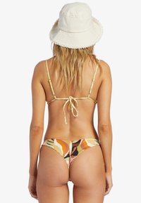 Bikini med multikolor abstrakt mönster i nyanser av orange, gult och brunt. Tunna justerbara remmar och design med knut i ryggen. Vit bucket hat.