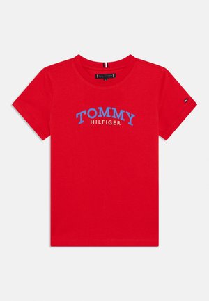 Maglietta rossa in cotone con scollo arrotondato, maniche corte e scritta blu "TOMMY HILFIGER", con piccolo logo sulla manica.
